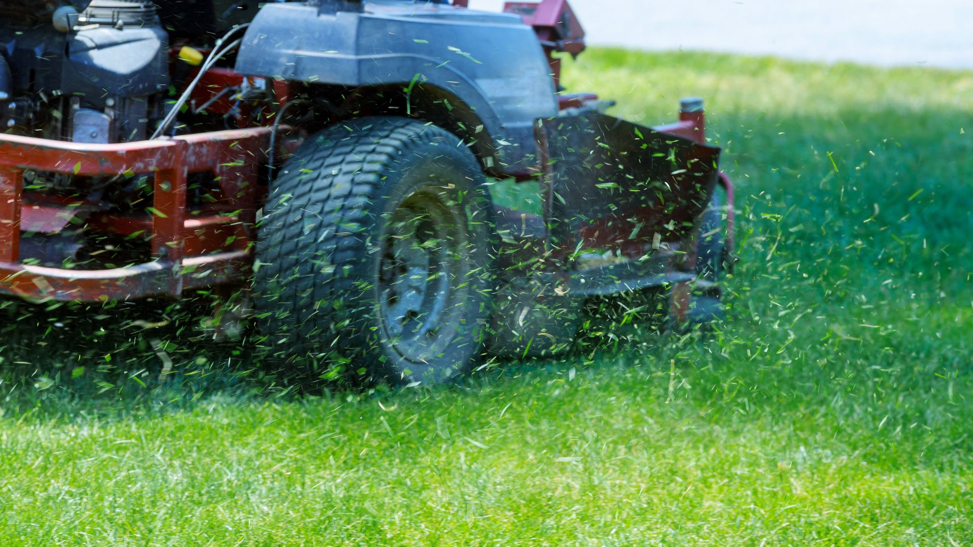 Zero-turn lawn mower cutting grass with flying grass clippings