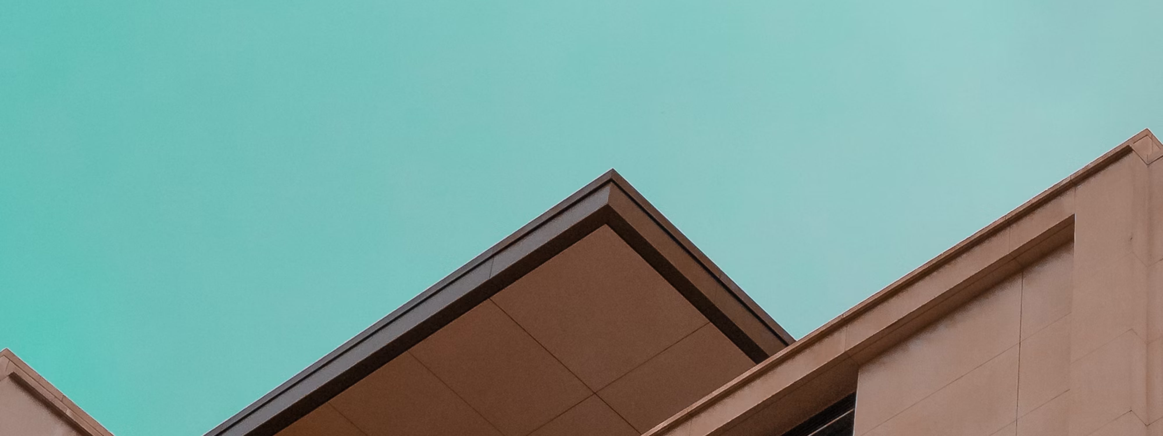 Modern building with angular roof against turquoise sky